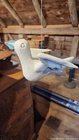 Side view of white dove flying decoy showing wing and tail detail, suspended by string.