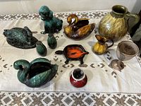 Full lot on table: includes swan planters, dog figurine, salt and pepper shakers, candle holder, creamer, goblet, and small ceramic items.