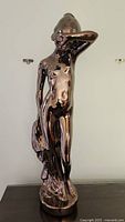 Full front view of the ceramic statue depicting a nude woman with copper luster finish.
