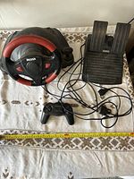Dexxa driving simulator controllers with steering wheel, pedal set, and gamepad connected by cables on table.