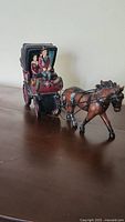 Photo showing side view of horse and buggy figurine with driver and two passengers.