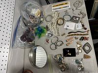 Overview of large jewelry lot spread out including watches, necklaces, bracelets, earrings, brooches, pins, and catch-all dish.