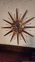 Front view of midcentury starburst wall clock mounted on wall.