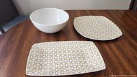 Full set of bowl, two rectangular plates, and a rounded square platter on wood table