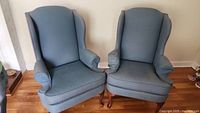 Pair of blue wingback chairs together showing overall condition and size