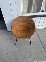 Wicker basket chair from front angle showing rounded seat and metal legs.