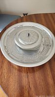 Full view of the large round hammered aluminum chip and dip platter with central lidded dip bowl, showing intricate pressed detailing on the tray and lid.