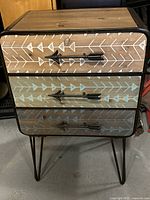 Full frontal view of the retro bedside table showing all three drawers and metal hairpin legs.