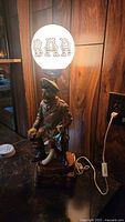 Full view of the sailor figurine lamp with globe light shade that reads 'BAR'.