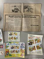 Stamps and collectibles laid out showing full sheets with characters, a newspaper clipping, and a story booklet.