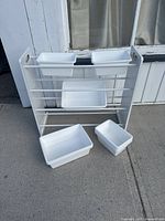 White metal storage rack with five white plastic bins positioned on and around it, showing the overall structure and setup.