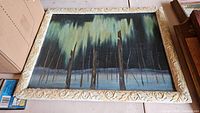Front view of abstract forest oil painting in carved wooden frame showing tree trunks and greenery with minor frame wear.