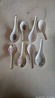 Top view of porcelain soup spoons showing floral decorated and plain designs.