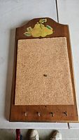 Front view showing wooden cork board with hand-painted pears above the cork center and 4 metal hooks below.