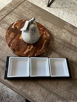 Full view with all items arranged: wood round board, stone pear, three white ceramic trays, and black holder.