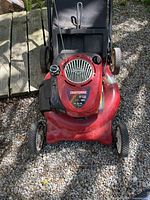 Top view of Craftsman lawn mower showing Briggs & Stratton engine and red metal deck on gravel surface.