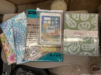 Four hard shell protective covers in various floral, mandala, and abstract designs in original packaging, laid out on a table.