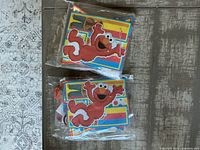 Two packages of Sesame Street themed paper banners with Elmo on them, colorful and brand new in plastic wrapping.