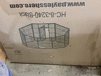 Photo of dusty, unassembled black metal pet playpen in original cardboard box showing model number HC-8-3240-Black and website www.pavlesshere.com on box.