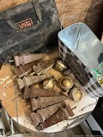 Photo of multiple brown wooden vintage furniture legs and gold-toned metal swivel wheels on a dusty surface.
