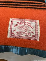 Close-up of the blanket label showing brand 'Mandarin Woolen Blanket' with Chinese text and 'Superior Quality' claim.