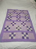 Full view of the purple patchwork quilt laid flat showing overall pattern and size.
