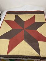 Full view of handmade star pattern quilt spread out on bed showing colors and design.