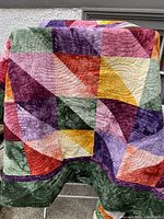 Front view of quilt showing geometric jewel tone patchwork design