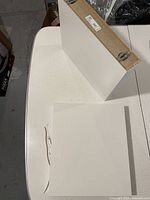 Top view of one white IKEA Lack shelf showing overall shape and finish on white table.