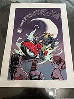 Front view of the Queens of the Stone Age concert poster featuring wolf-headed rider on motorcycle with three women in foreground and large moon background.