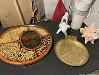 Image of vintage lot showing round handmade resin display with natural items, brass dish, ceramic creamer, large shell, and ceramic pitcher