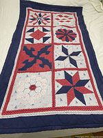 Full view of vintage red, white and blue handmade quilted blanket showing block patchwork designs and borders.
