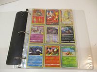 Opened binder showing 9 holo Pokémon cards featuring a variety of types including fire, water, and colorless.