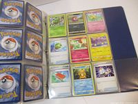 Photo of binder showing Pokemon cards in clear sleeves. Cards include various Pokemon creatures, energy, and item cards.