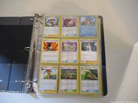 Open binder page showing 9 Pokemon cards in plastic sleeves, with various trainer and item cards visible.