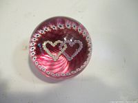 Top down close-up of paperweight showing two intertwined hearts and flower ring detail