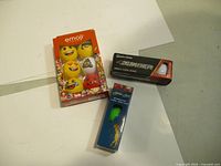 Golf balls and tees arranged on a white surface, showing emoji golf balls, TaylorMade Burner golf balls, and golf tees.