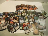 Multiple Magic: The Gathering cards laid out on a white surface showing a mix of different colors and card types.