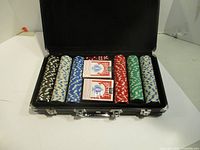 Full poker set in black carrying case showing chips, cards, and dice.