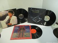 Three vinyl albums displayed with records partially out of their sleeves: Michael Jackson Thriller, James Brown Bodyheat, and Supertramp Crime of the Century.