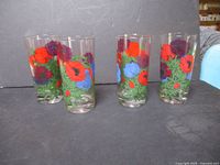 Set of 4 tall clear glasses with colorful hand-painted poppy flowers in red, purple, and blue with green leaves and stems.