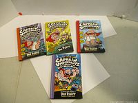 Four Captain Underpants books arranged on a white background showing front covers with colorful comic-style illustrations and titles.