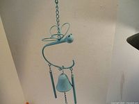 Blue metal dragonfly wind chime hanging, showing curved dragonfly shape with central bell and two tubular chimes.