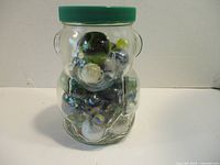 Front view of bear-shaped glass jar filled with various marbles showing colorful and clear marbles inside.