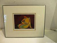 Full view of framed artwork depicting a stylized mother and child with colorful flowing lines on a dark background, framed with cream mat and black frame.