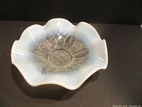 Top view of the opalescent glass bowl showing the floral and leaf embossed pattern and the ruffled edge.