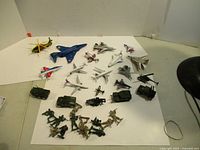 Wide view showing toy planes, army vehicles, and toy soldiers on white background.