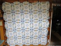 Quilt fully displayed showing double wedding ring quilt pattern with floral pastel fabrics and star blocks on white background