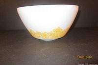 Side angle showing white vintage milk glass bowl with yellow floral pattern along the base.