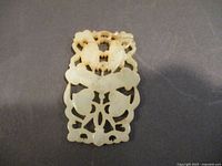 Front view of vintage jade pendant showing detailed carvings and natural color variations.